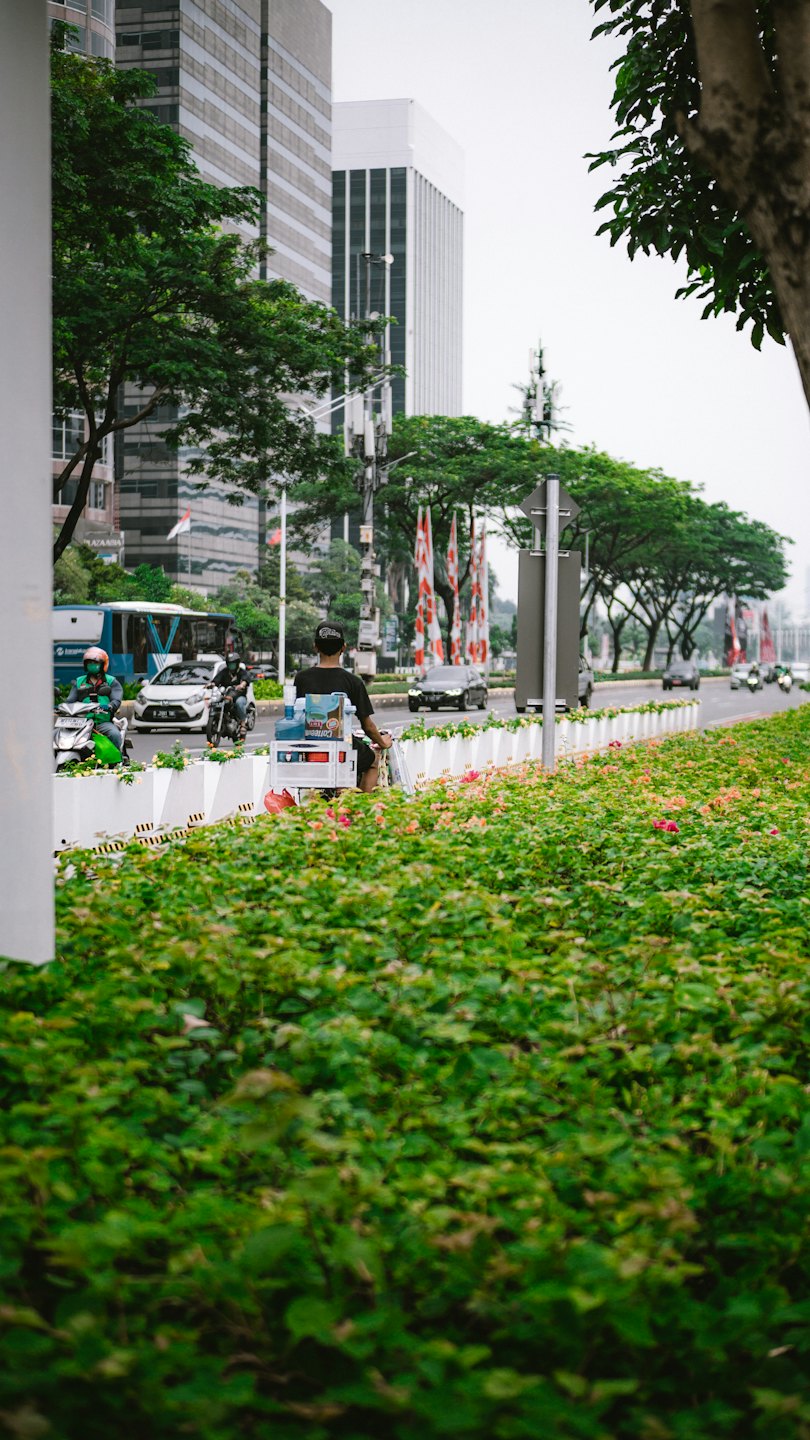 Delivery driver on a scooter rides down a busy city street.