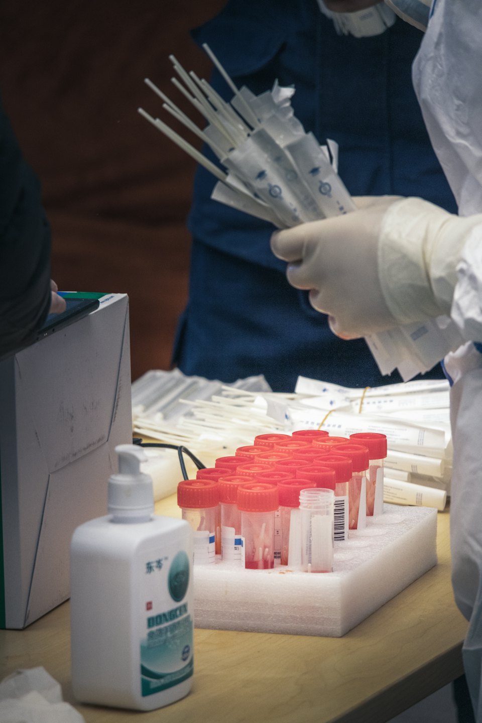 Healthcare worker holding medical swabs over a table with supplies.